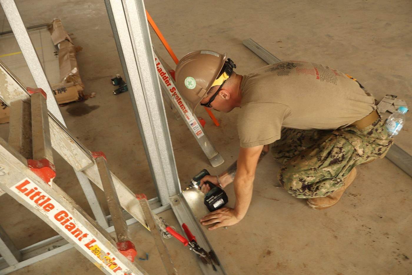 Worker fastening metal stud framing, a scope measured in drywall and framing takeoffs